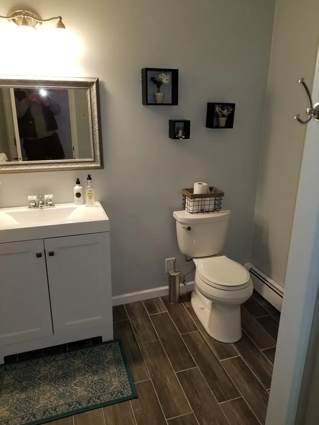 Finished bathroom with wood-look tile, white vanity and fixtures installed by Cedar Tough Builders
