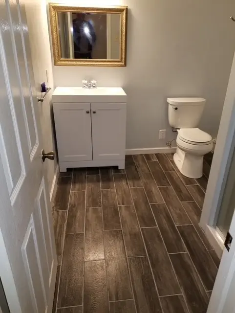 Completed bathroom with wood-look tile and white vanity