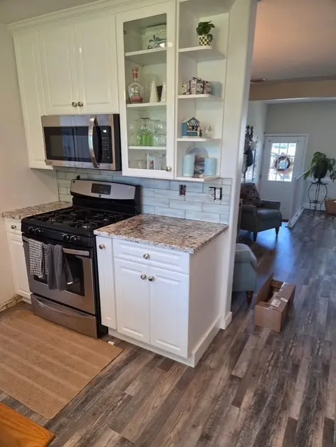 Finished kitchen range wall with white cabinetry and subway tile
